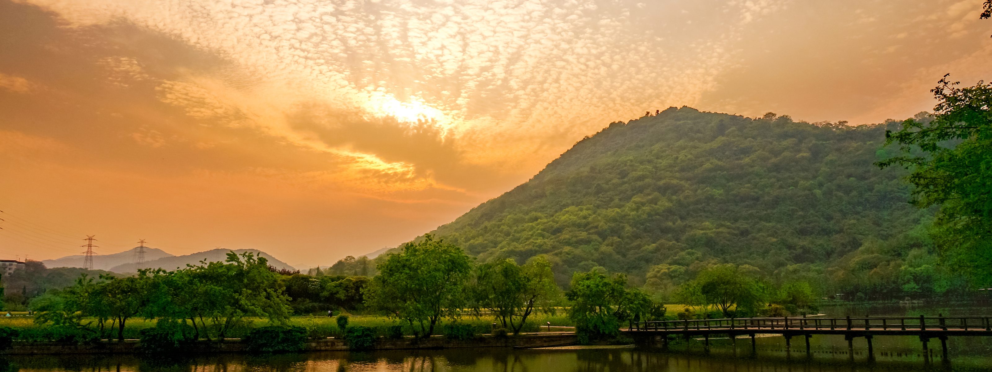 A still lake below wooded hills at sunset